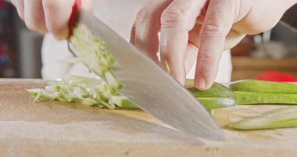 Slow motion close up of a chef knife slicing a cucumber alt