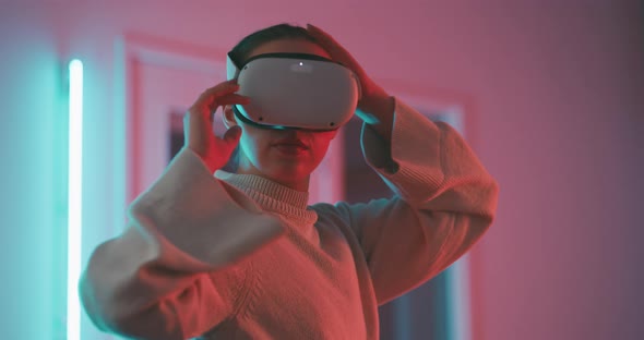 Close up of a young woman taking off virtual reality goggles and looking into the camera alt
