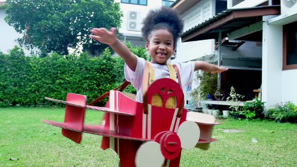 Happy child playing with a toy paper plane in the house.