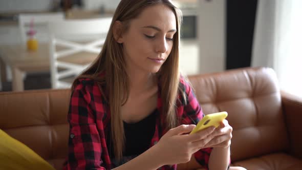 Beautiful young woman writing text message on her smartphone alt