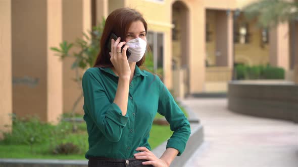  Girl in a Medical Mask Talking on the Phone Outside