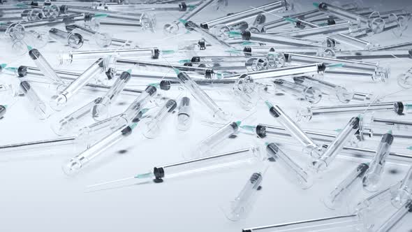 Looping animation with a pile of used clear plastic disposable syringes. 4K