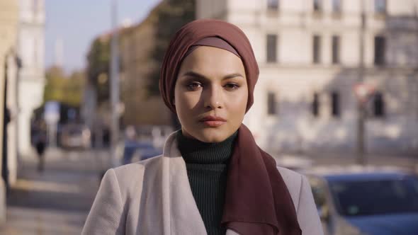 A Young Beautiful Muslim Woman Looks Seriously at the Camera in a Street in an Urban Area  Closeup alt