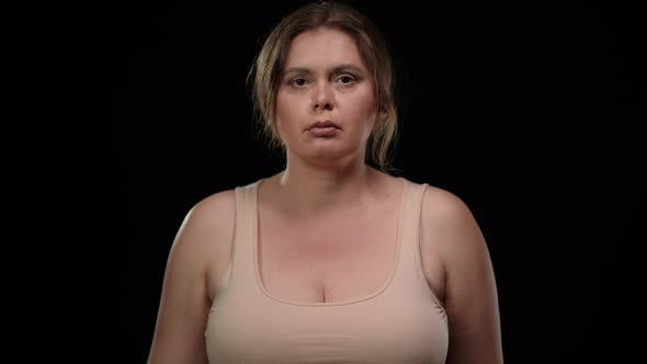 Serious Plus Size Woman Putting Hand on Chest Raising Palm Swearing at Black Background alt