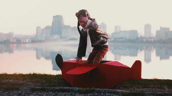 Little Happy Pilot Boy Getting Into Fun Red Cardboard Plane Costume at Amazing Peaceful City Lake alt