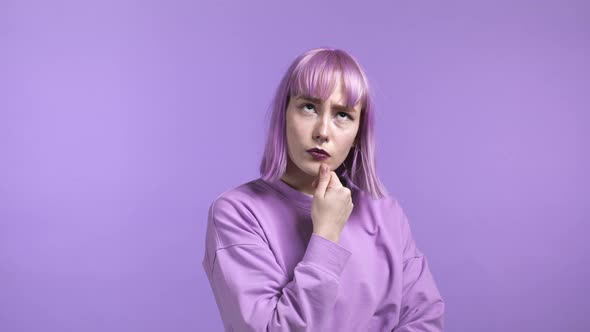 Thinking Woman with Dyed Purple Hair Looking Up on Violet Studio Background alt