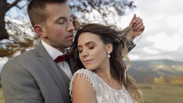 Lovely Young Newlyweds Bride and Groom Embracing Hugging on Mountain Slope Wedding Couple in Love alt