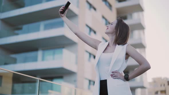 Fashionable Woman Smiling and Taking Selfies on Smartphone in City