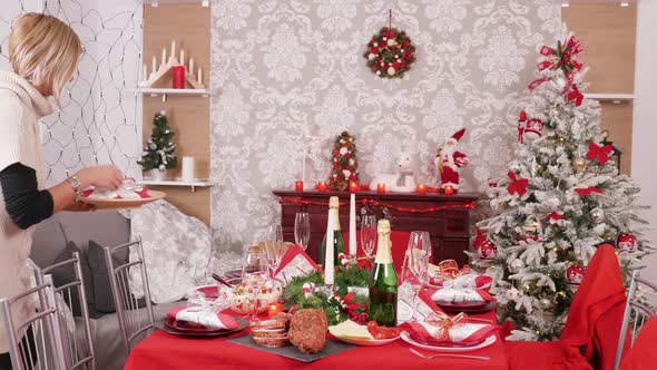 Young Beautiful Woman Preparing Dinner Table for Christmas Celebration alt