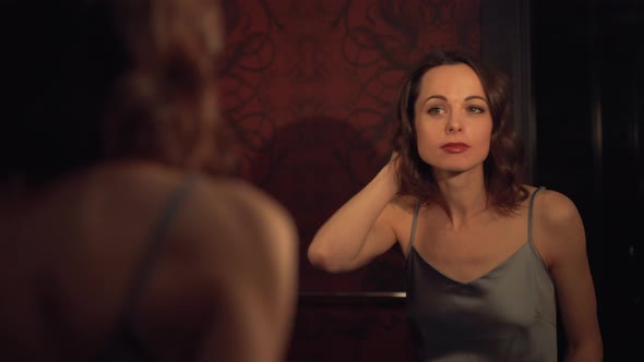 Attractive woman at the mirror turns off the light indoors alt