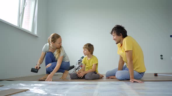 A Family of Mother Father and Son Install Laminate on the Floor in Their Apartment alt