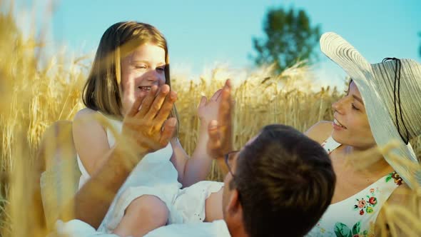 Little daughter clapping hands with father on family picnic in countryside alt