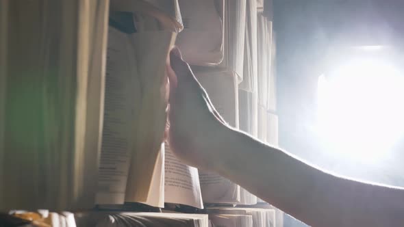 Woman Walks Along Wall with Books and Runs Hand Over Pages alt