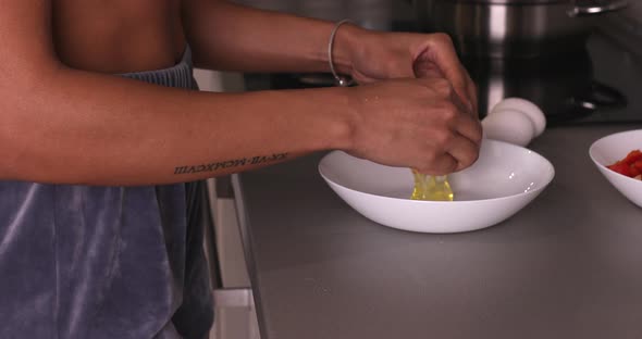 Woman cracking egg into bowl reveal egg yolk.