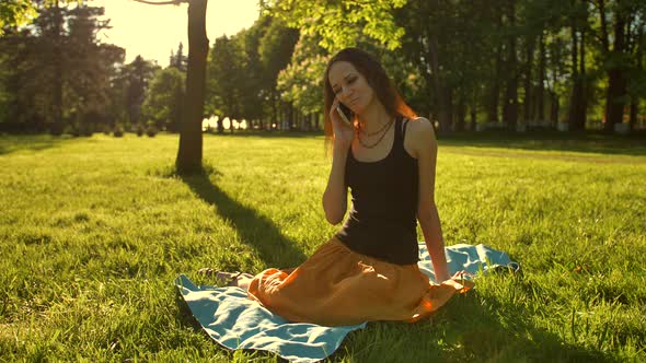Woman Sit, Talk During a Phone Call Outdoors in the Park alt