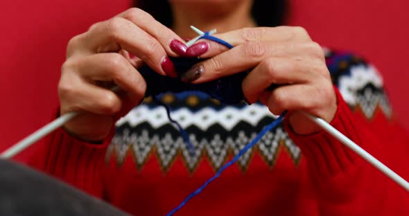 Hand of mature female sitting in comfortable sofa and knitting alt