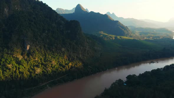 Aerial: flying over Nam Ou River Nong Khiaw Muang Ngoi Laos, sunset dramatic sky alt