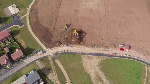 Aerial view of escavator at work on red soil to build new houses in England