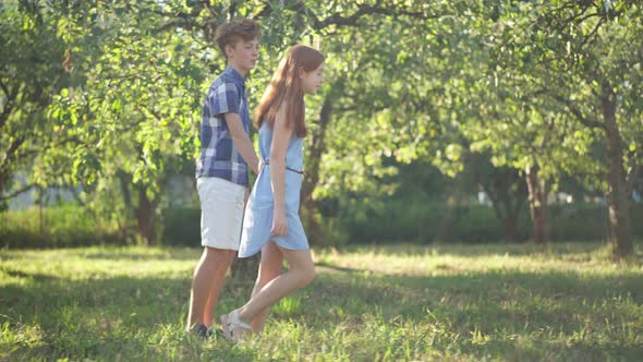 Side View Wide Shot Happy Loving Teenage Couple Holding Hands Running in Sunshine Outdoors alt
