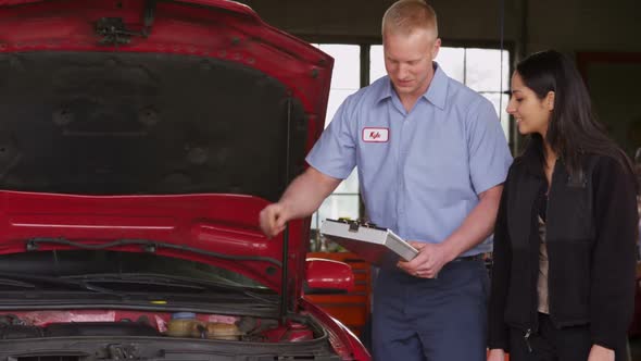 Mechanic in auto repair shop works with customer alt