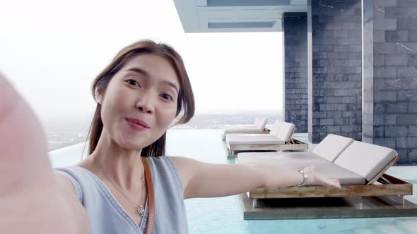 Happy young Asian woman using a smartphone for making selfie and video call on social media, smiling alt