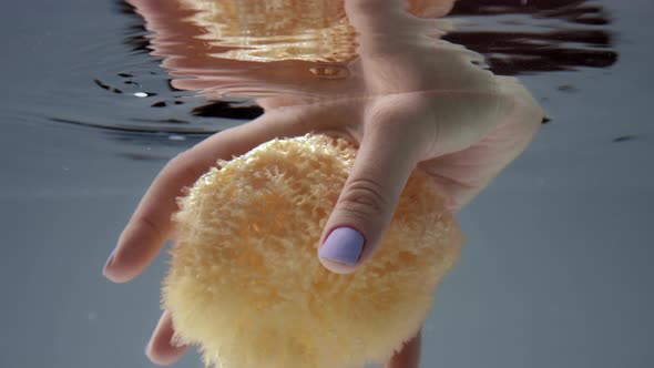 Woman Hand with a Bath Sponge Underwater View