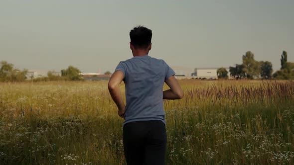 Running Man On Green Grass Field.Slow Motion Running Man Exercising On Trail.Man Running On Park alt