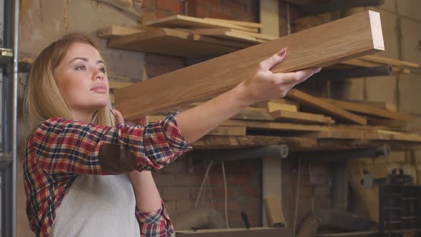 Professional Young Carpenter Lady Examining Wooden Piece After Grinding