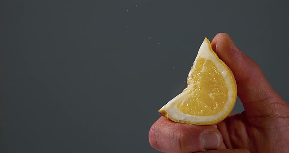 Hand of Man Squeezing Lemon, citrus limonum against Black Background, Slow Motion 4K alt