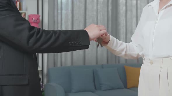 Close Up Of Real Estate Agent's Hand Giving The Keys To A Woman In The House For Sale alt