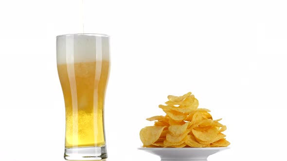 Beer and chips. Pouring beer in glass on white background. 4K UHD video alt