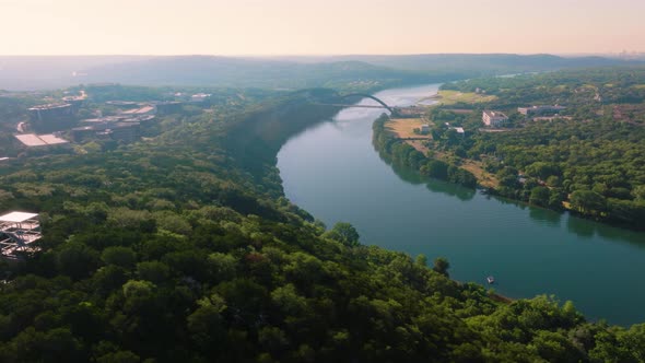 Flying over greenbelt in Austin, Texas near 360 Pennybacker bridge during hazy summer sunrise, 4k la alt