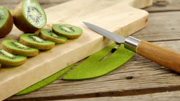 Slices and half section of kiwi on chopping board alt