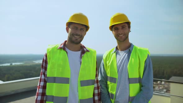 Professional Construction Workers in Safety Helmets and Jackets Smiling Camera