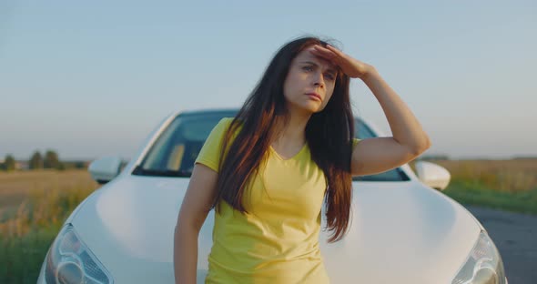 Girl on Side of Road Looking Out for Oncoming Cars alt