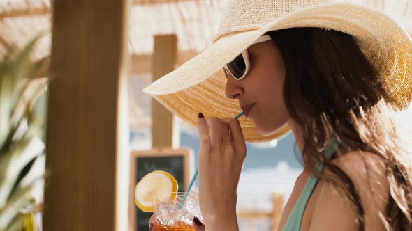 Smiling young girl having a cocktail at the beach