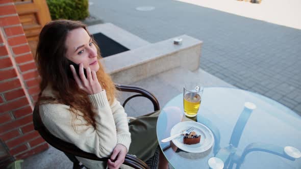 Girl Sit in a Cafe on the Street Talking on the Phone