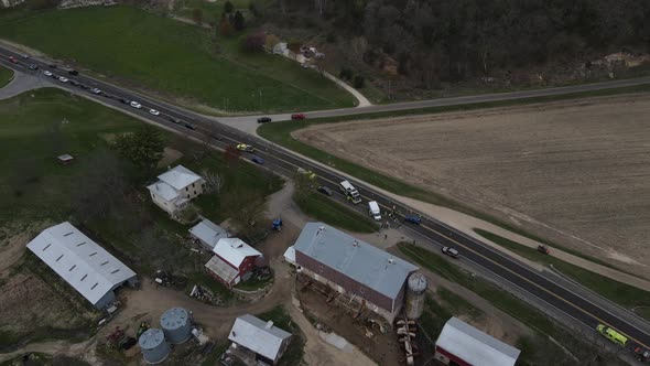 Highway running through rural view with traffic backed up due to accident in front of farm house.