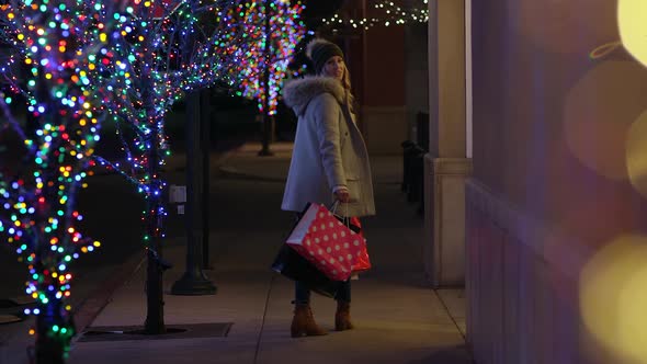 Woman walking down sidewalk and turns to look over shoulder alt