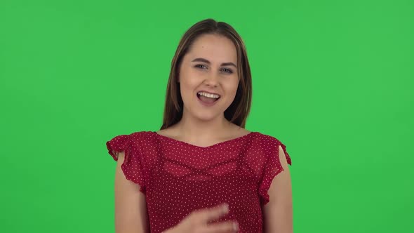 Portrait of Tender Girl in Red Dress Is Making a Rock Gesture and Enjoying Life. Green Screen alt