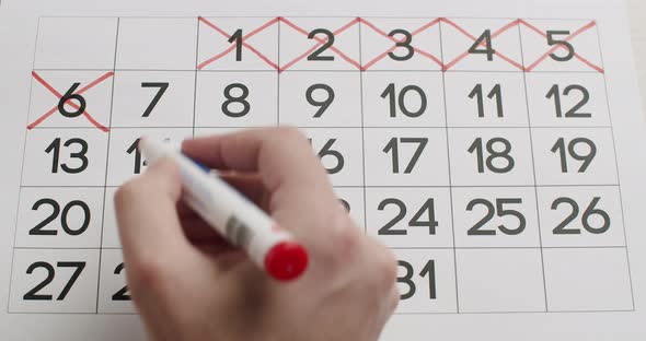 Man's Hand Write Down the 678910Th Day on the Paper Calendar Using a Red Pen alt