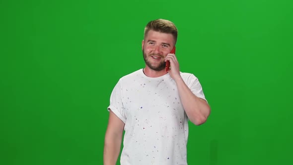 Portrait Bearded Guy Calmly Walking and Talking on the Mobile Phone on Greenscreen. Chroma Key alt