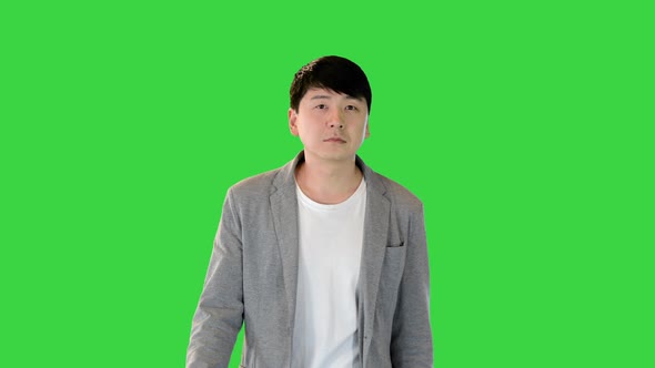 Young Asian Man in Casual Clothes Walks Looking Around on a Green Screen Chroma Key