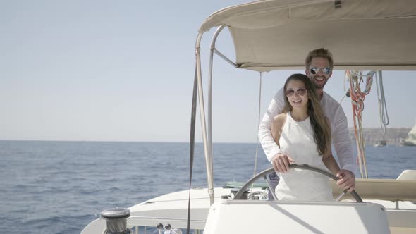 Romantic Owner Couple Steering Their Catamaran Together alt