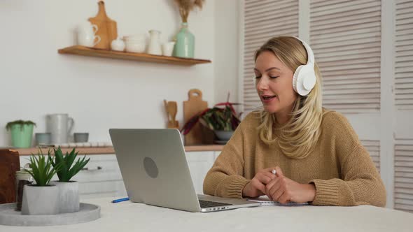 Woman in Headphones Communicating By Video Call on Laptop alt