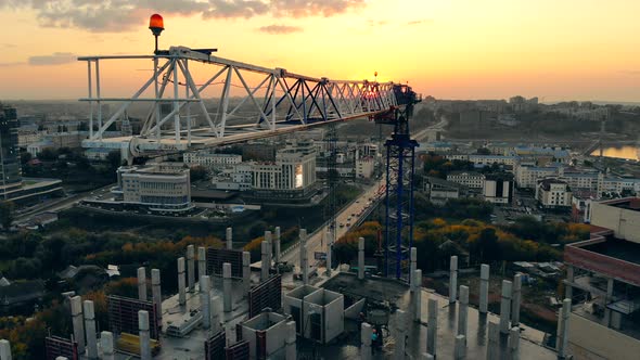Moving Building Crane at the Sunset Project Site. Modern Construction Site at Sunset, Aerial View. alt