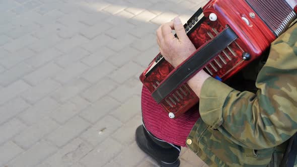 Caucasoid Senior Man Street Musician Plays His Music on the Harmonica in the City Square in the Open