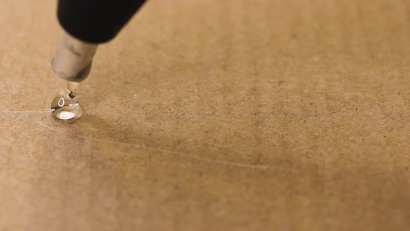 Close Up View of a Glue Gun Applying Hot Silicone Drops to a Surface alt