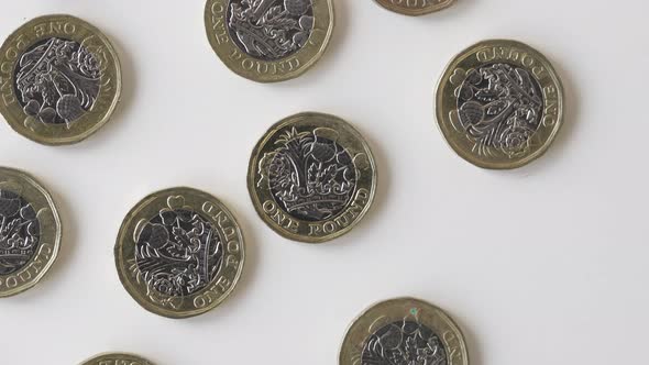 Gold And Silver British One Pound Coins Laid Flat On A White Table - British Money - Overhead Shot alt