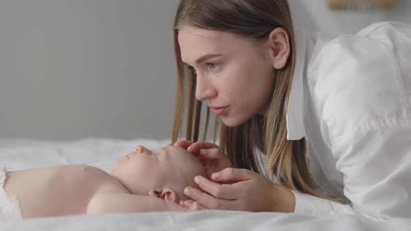 Mother Touching and Kissing Sleepy Adorable Infant alt